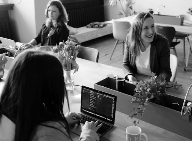 Three talking women in the office with a purple photo filter